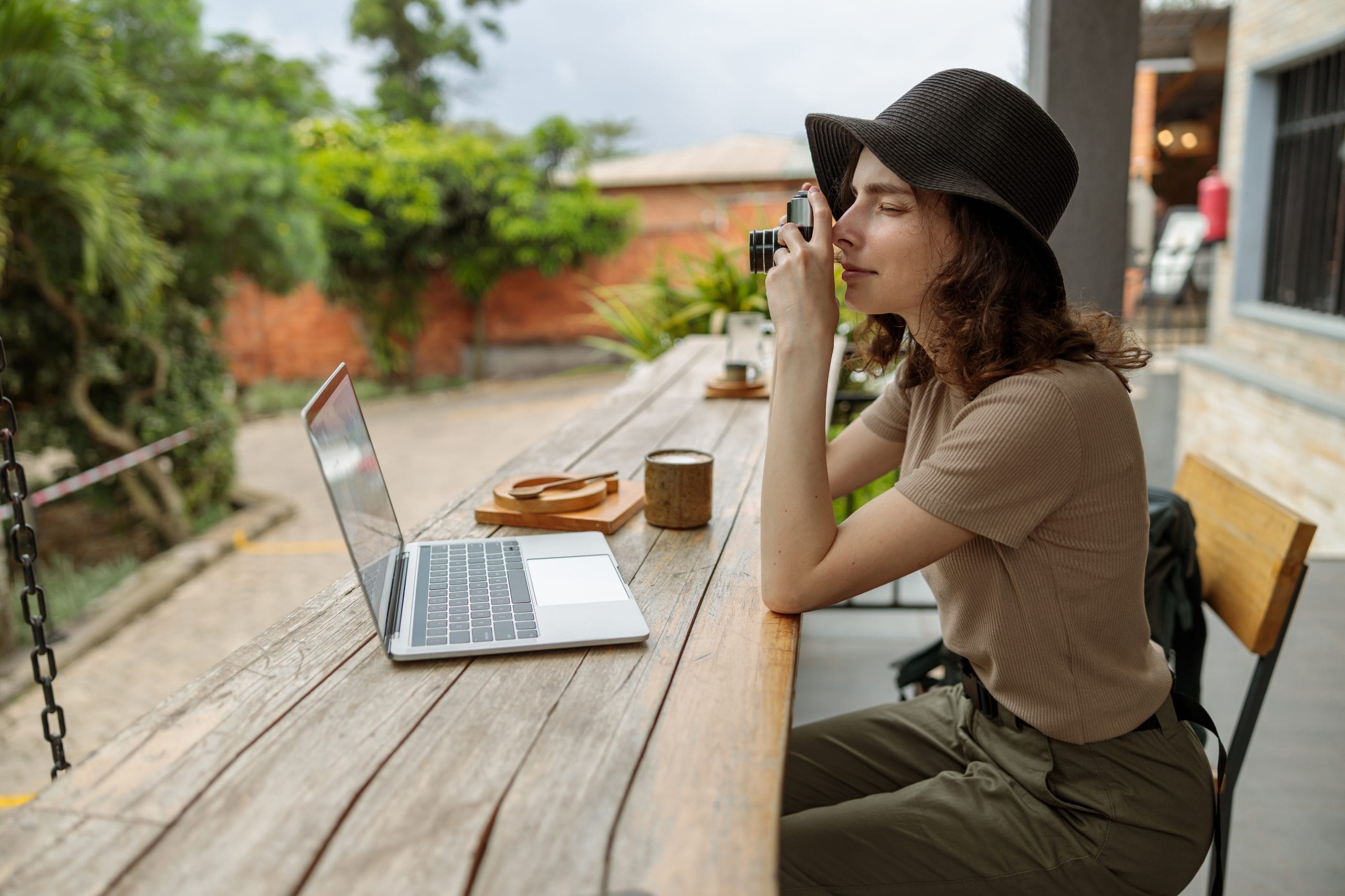 Young female traveler making photo while sitting in cafe outdoors
